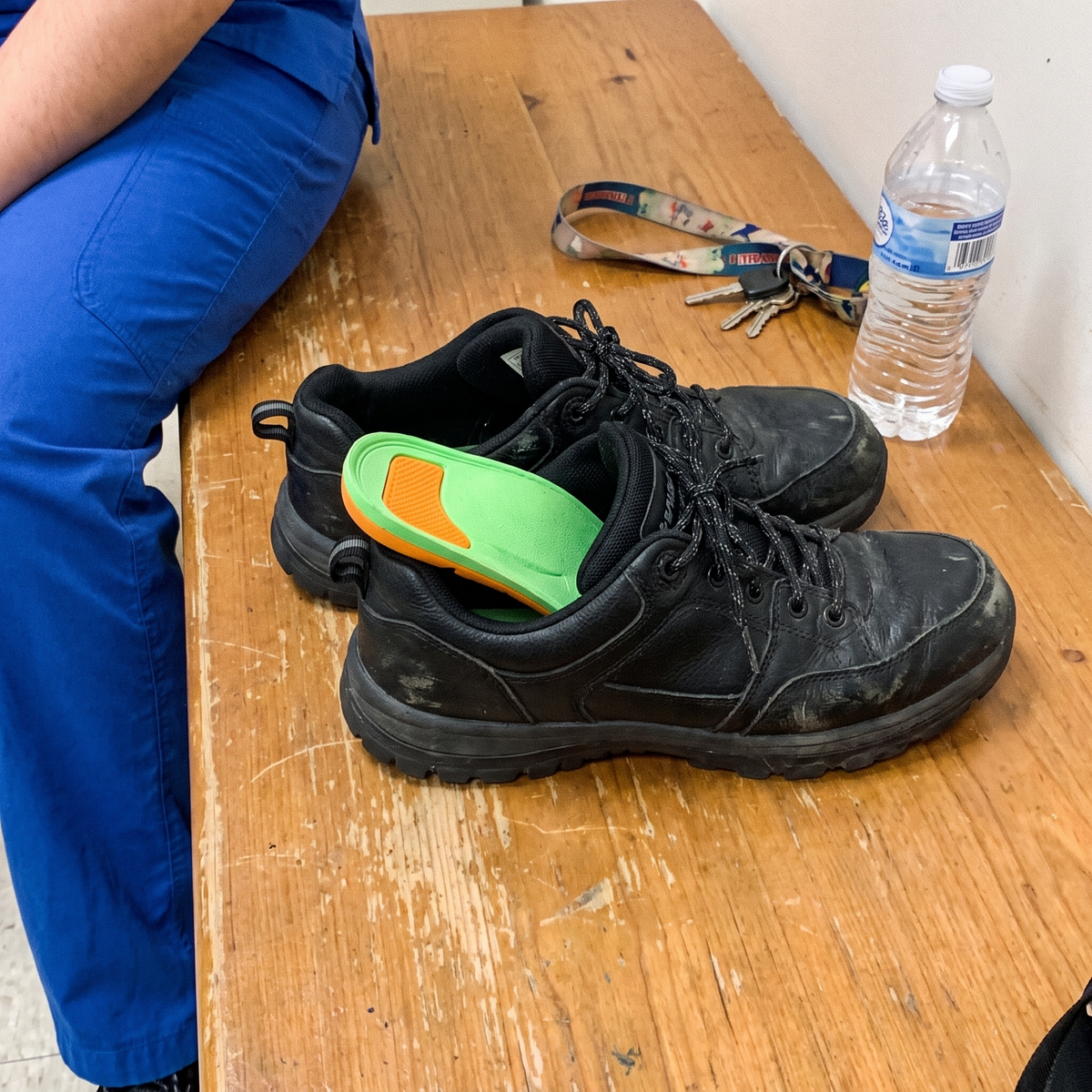 Work sneakers on a break room bench with the arch support insole half inserted