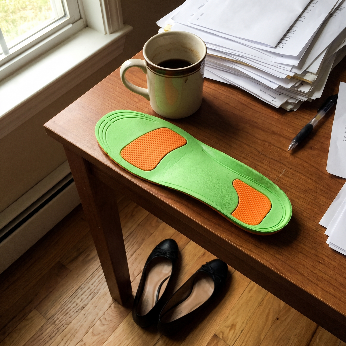 Arch support insole on a desk next to a coffee mug