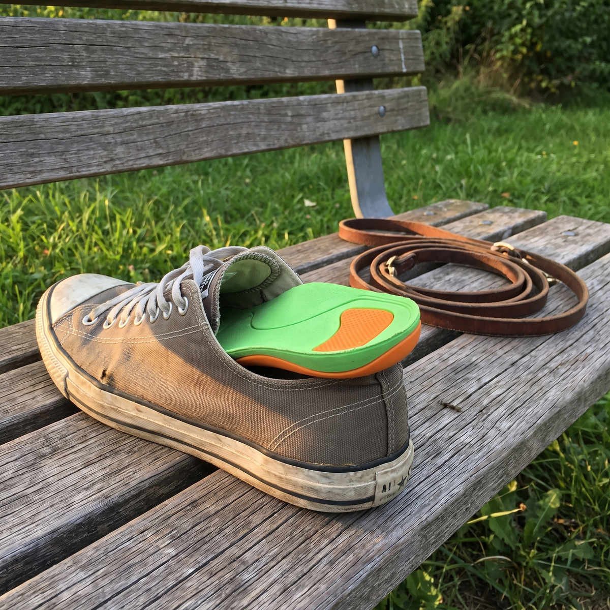 Sneaker on a park bench with the arch support insole pulled halfway out