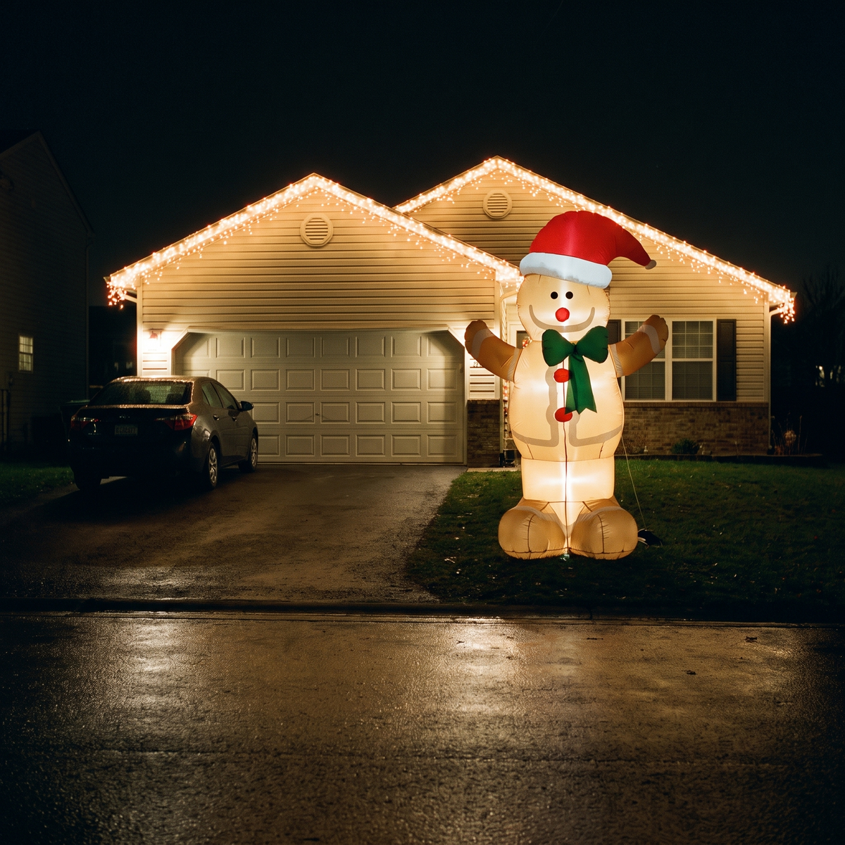 Decorated house at night with the inflatable gingerbread man lit on the front lawn