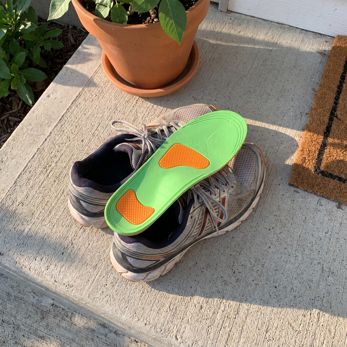 Running shoes on a porch step with the arch support insole on top