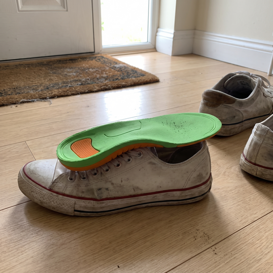 Orthotic arch support insole resting on a white sneaker by the front door