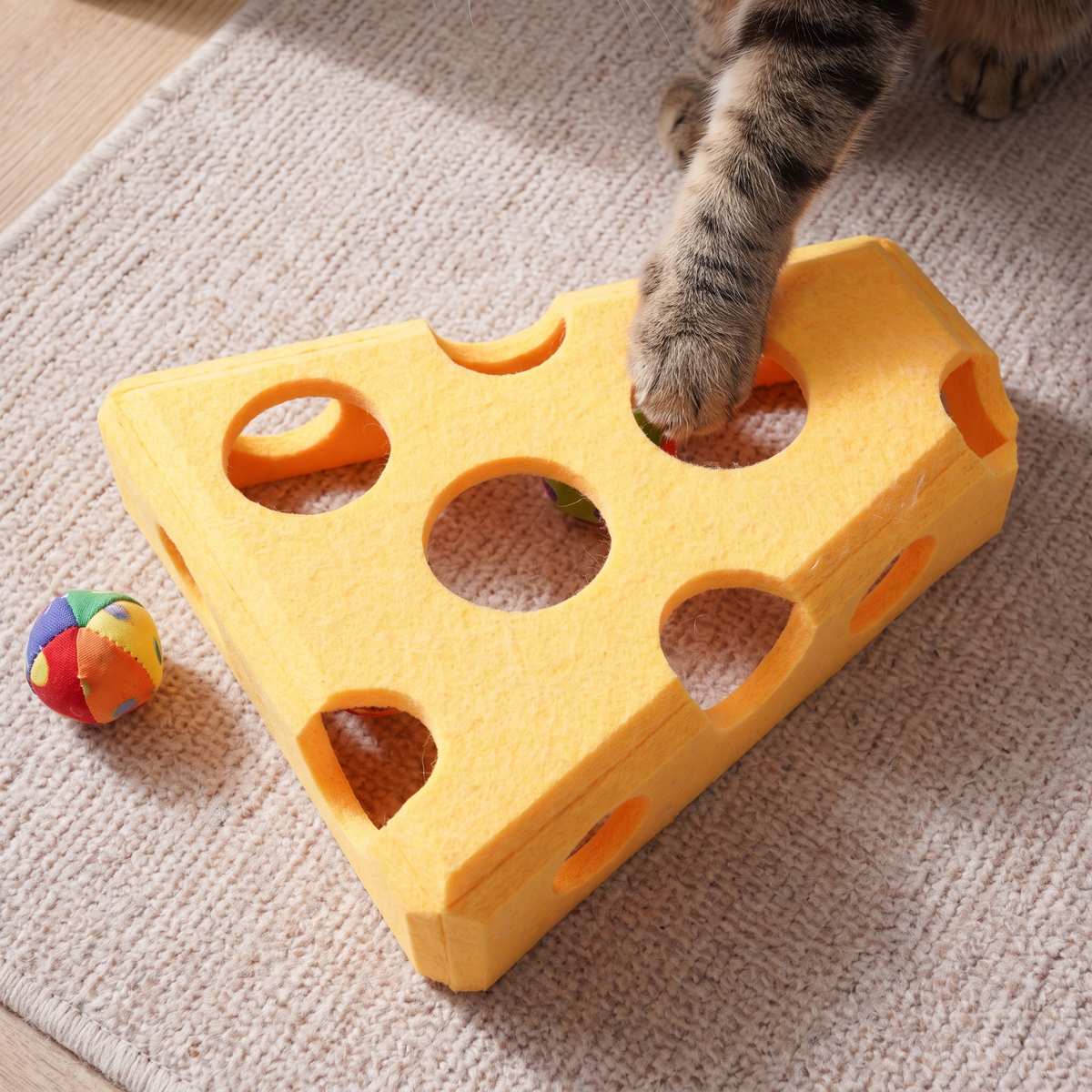 Top-down view of the felt cat puzzle box with a cat's paw in one hole