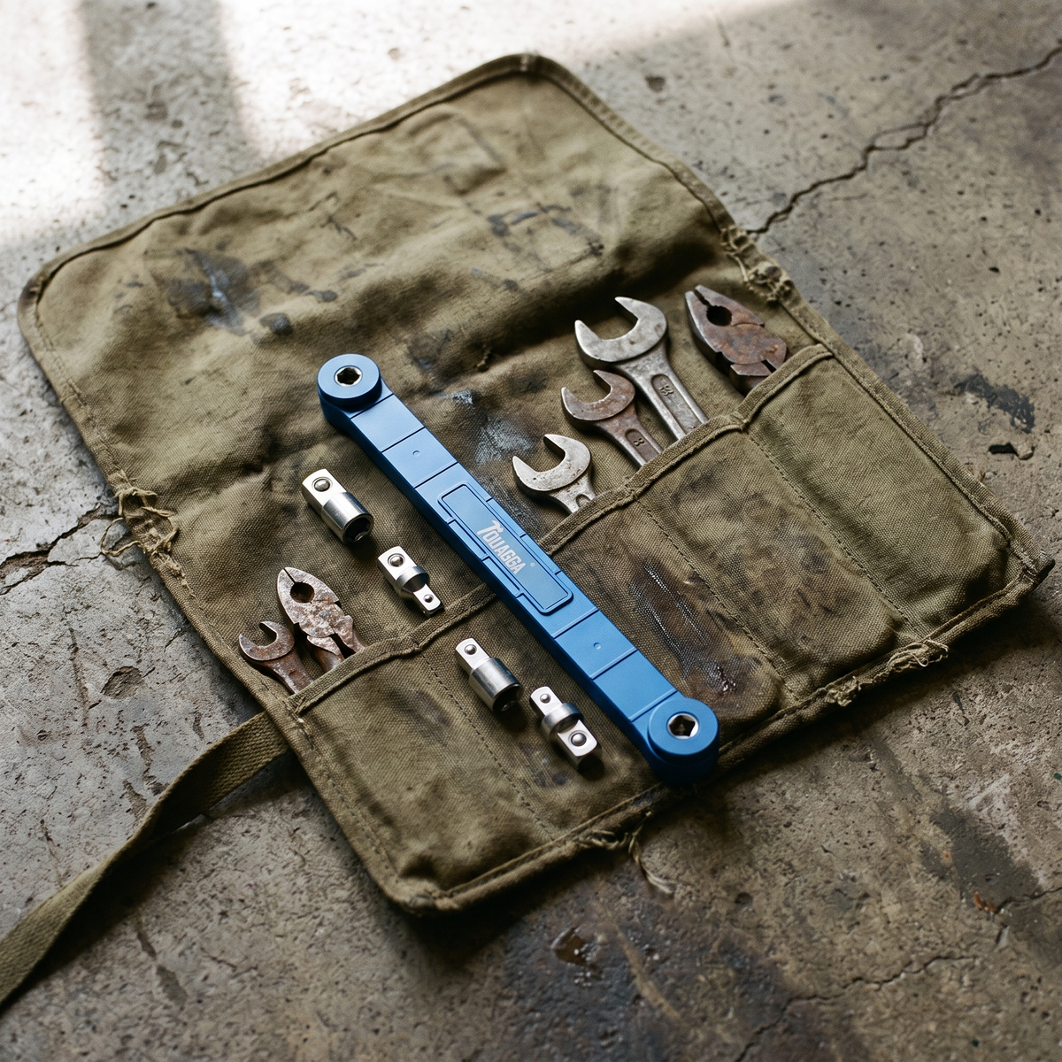Extension wrench in an open tool roll with spanners and pliers