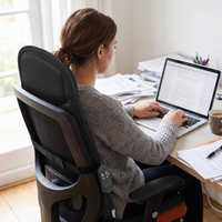 Woman working at a home office desk leaning back against the heated massage seat cushion on her chair